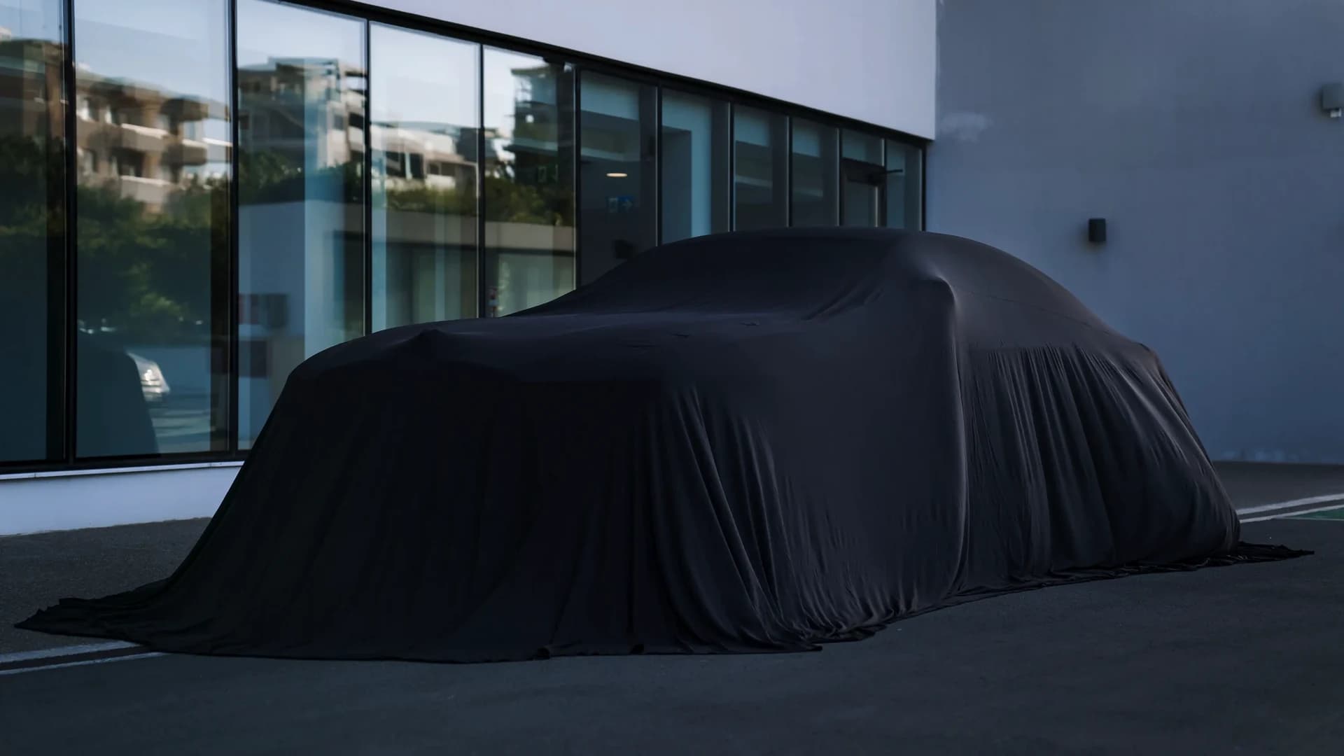 Side profile of a black Rolls-Royce Spectre outside a glass-fronted building