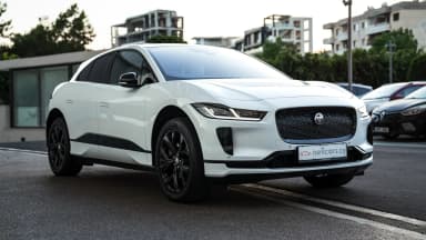 Rear three-quarter exterior view against an urban backdrop. Car 85