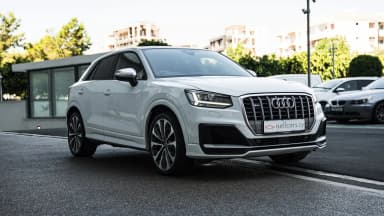 Front three-quarter view against an urban backdrop. Car 87