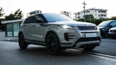 Front three-quarter view with black alloy wheels against an urban backdrop. Car 89
