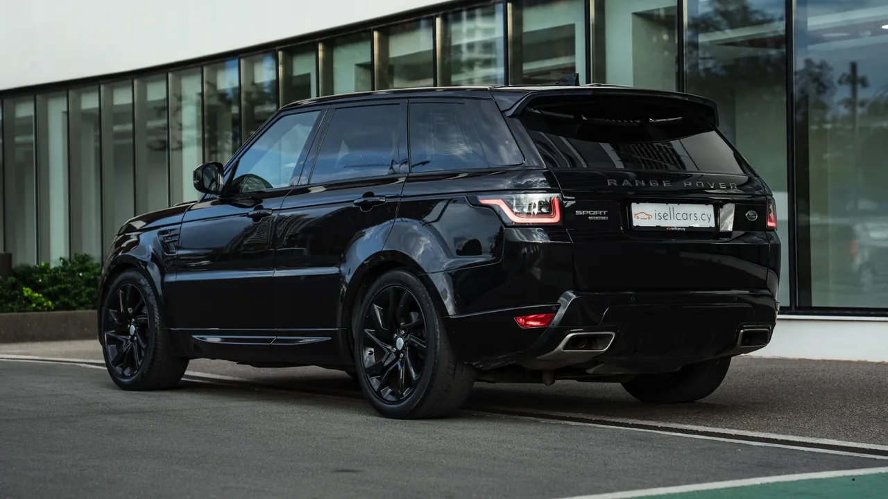 Rear three-quarter view by the glass showroom facade, black wheels and twin exhausts. Car 95